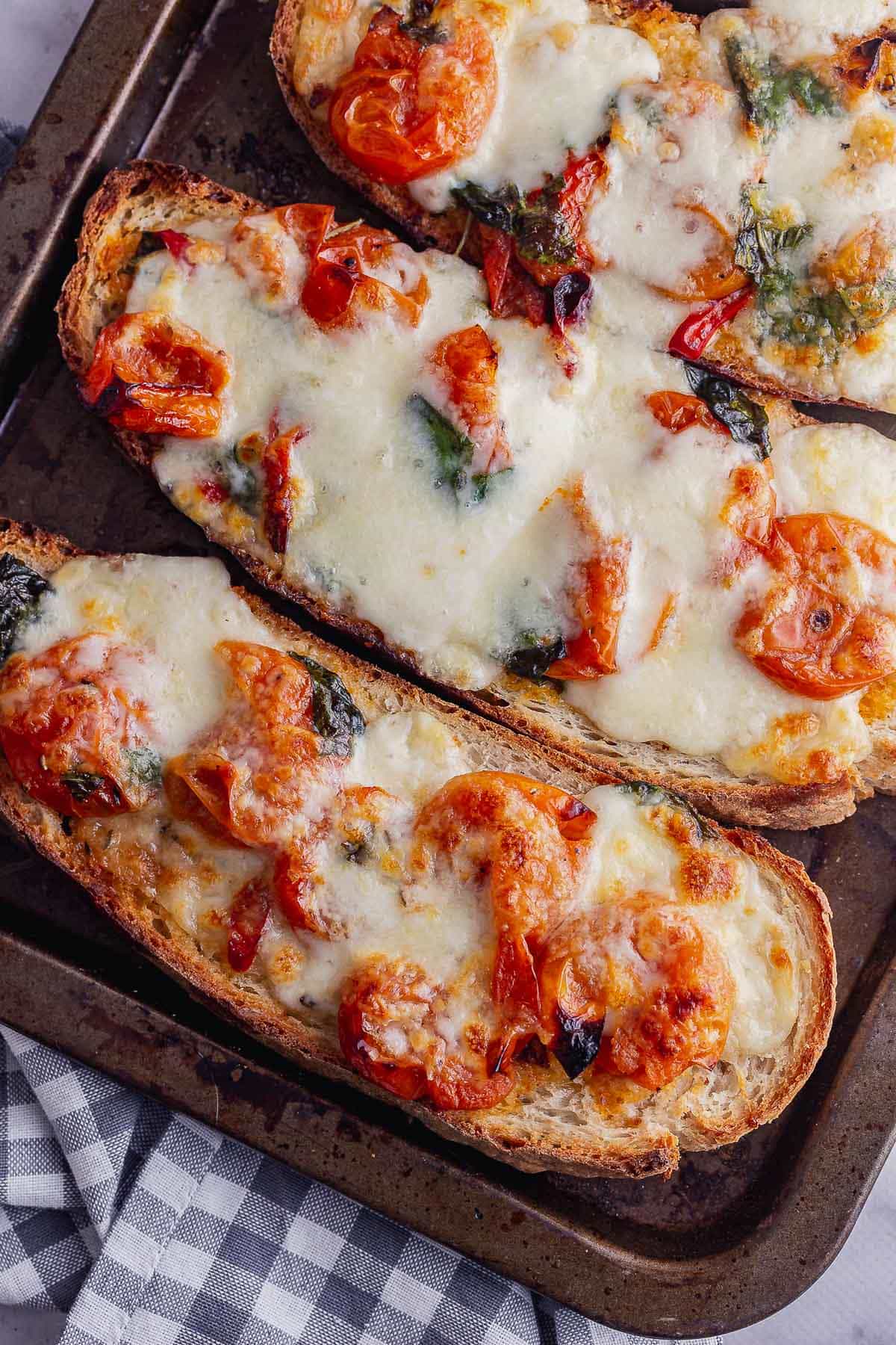 Close up of mozzarella and tomato toasts with a checked cloth