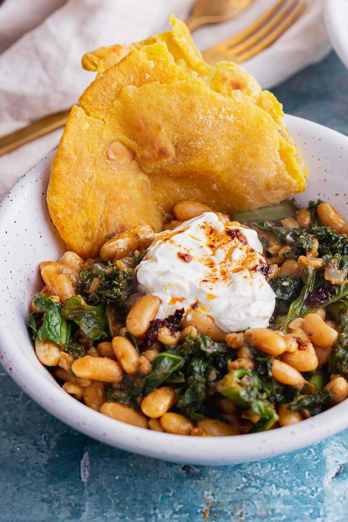Close up of bean and pearl barley stew with roti in a white bowl