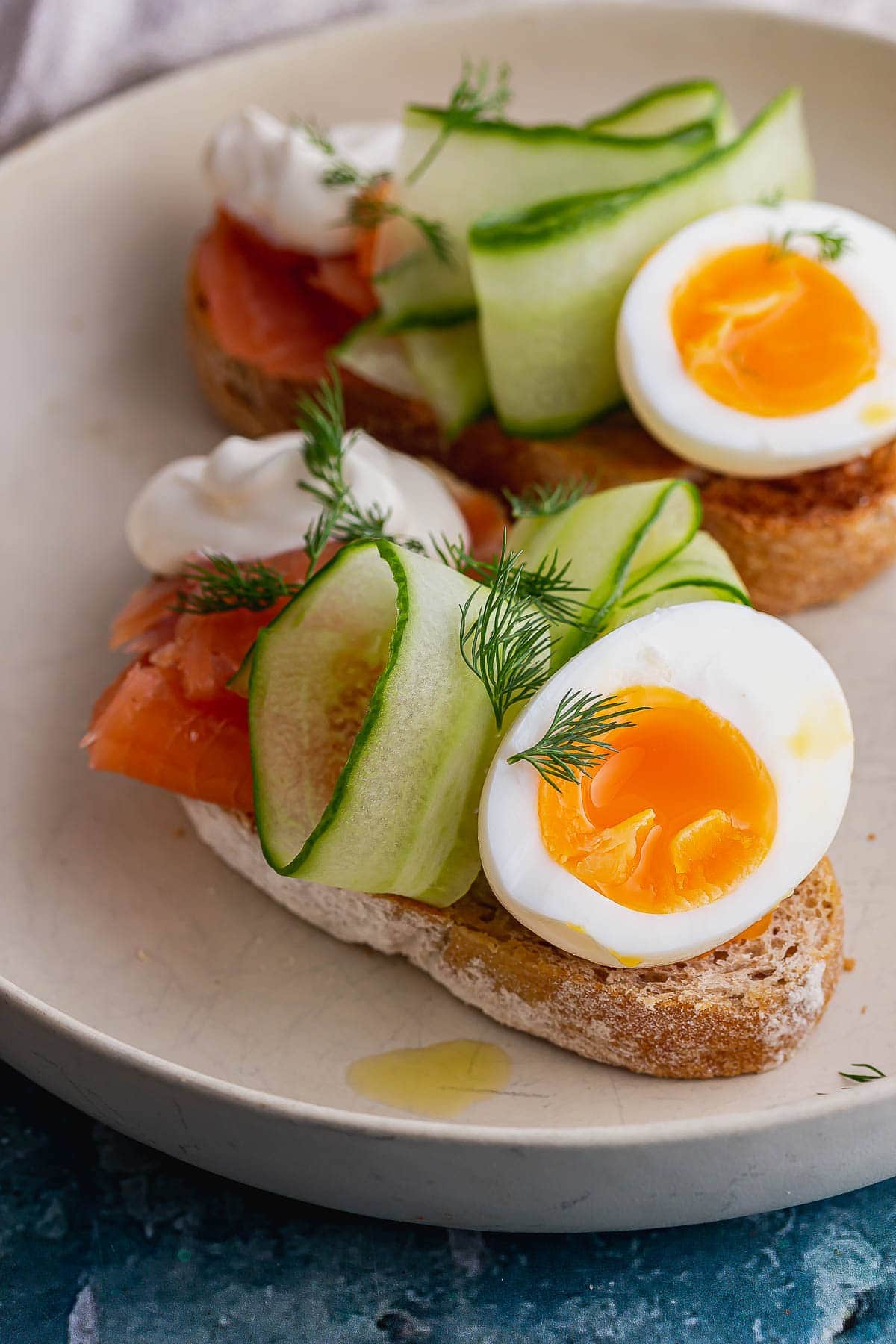 Close up of runny eggs on toast with salmon and cucumber