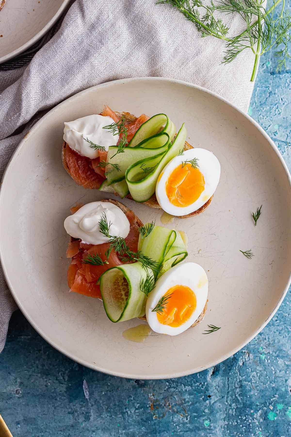 Overhead shot of smoked salmon toasts with boiled eggs and cucumber