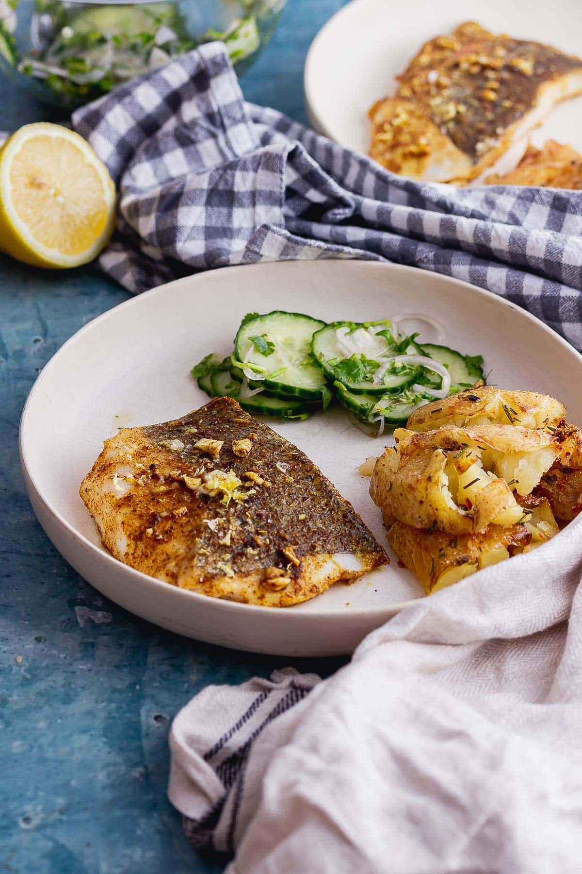 White bowl of baked fish with cucumber and cream cloth