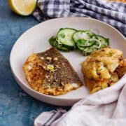 White bowl of baked fish with cucumber and cream cloth