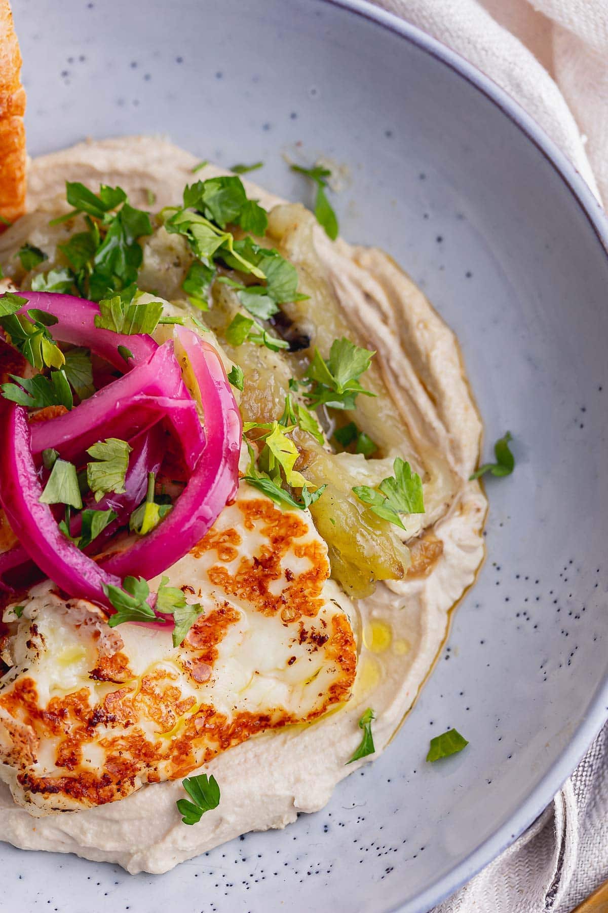 Close up of smoky aubergine and halloumi bowl with pink pickled onions