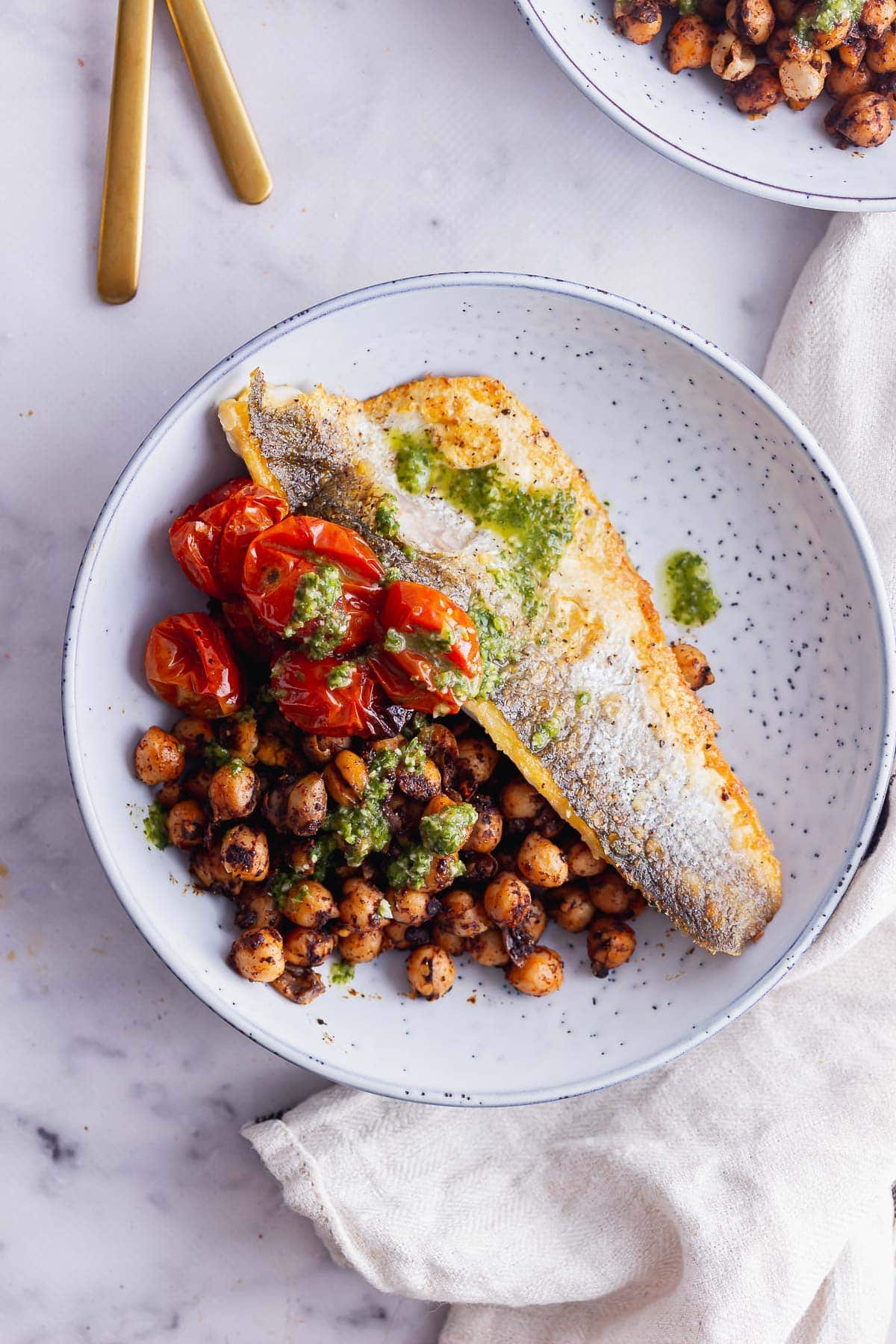 Overhead shot of fried sea bass and chickpeas in a blue bowl