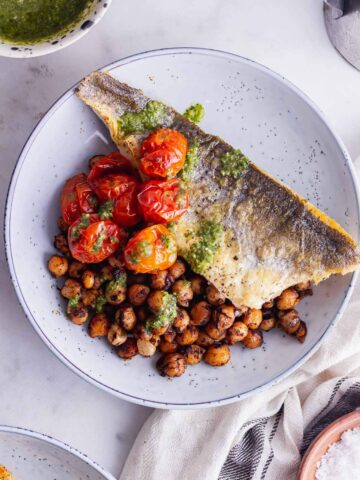 Overhead shot of crispy skin sea bass with tomatoes and chickpeas