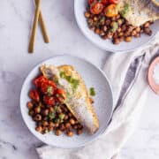 Overhead shot of crispy skin sea bass with tomatoes and chickpeas