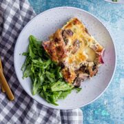 Blue bowl of brunch bake with salad on a checked cloth