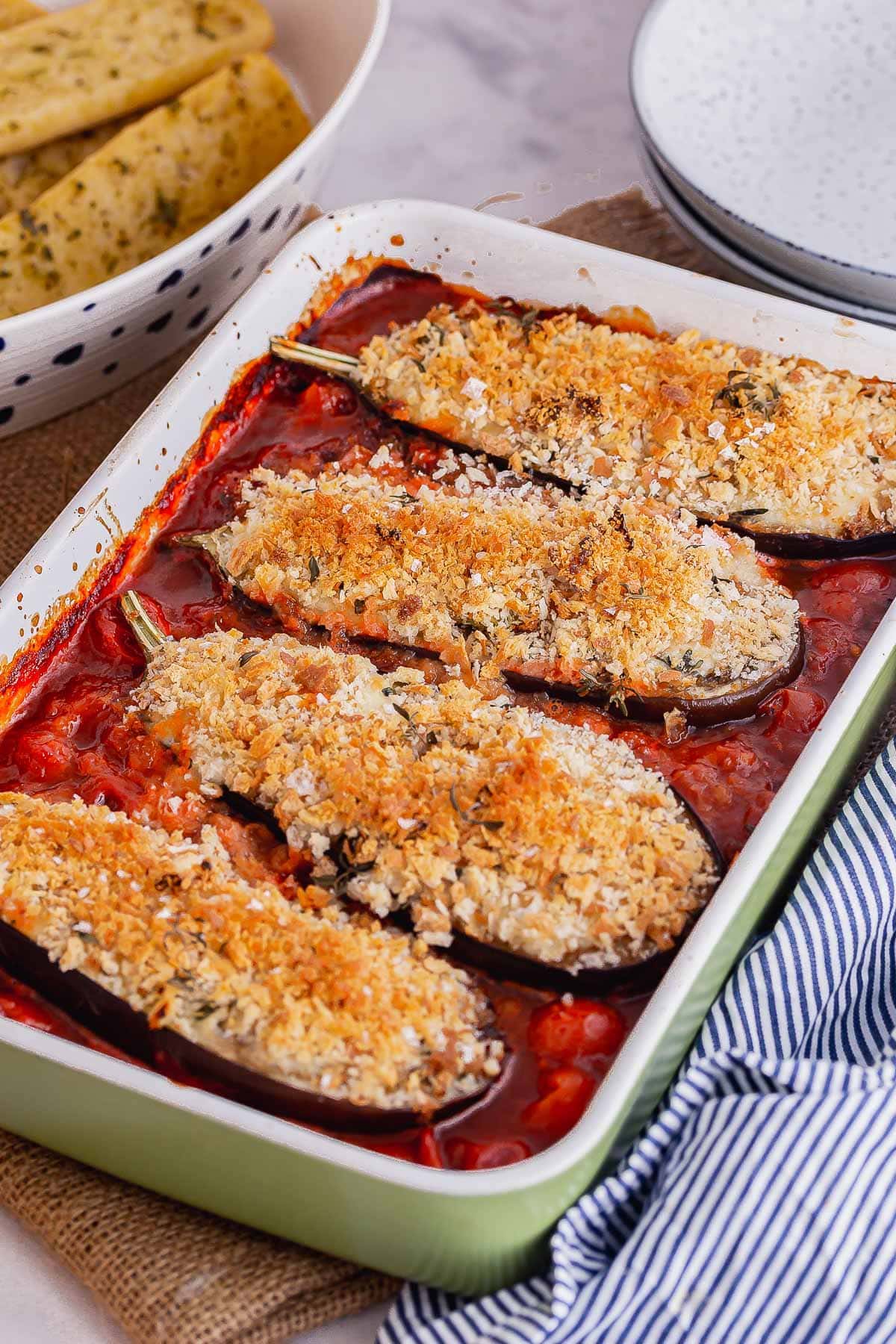 Green baking dish with cheesy roasted aubergines and tomato sauce