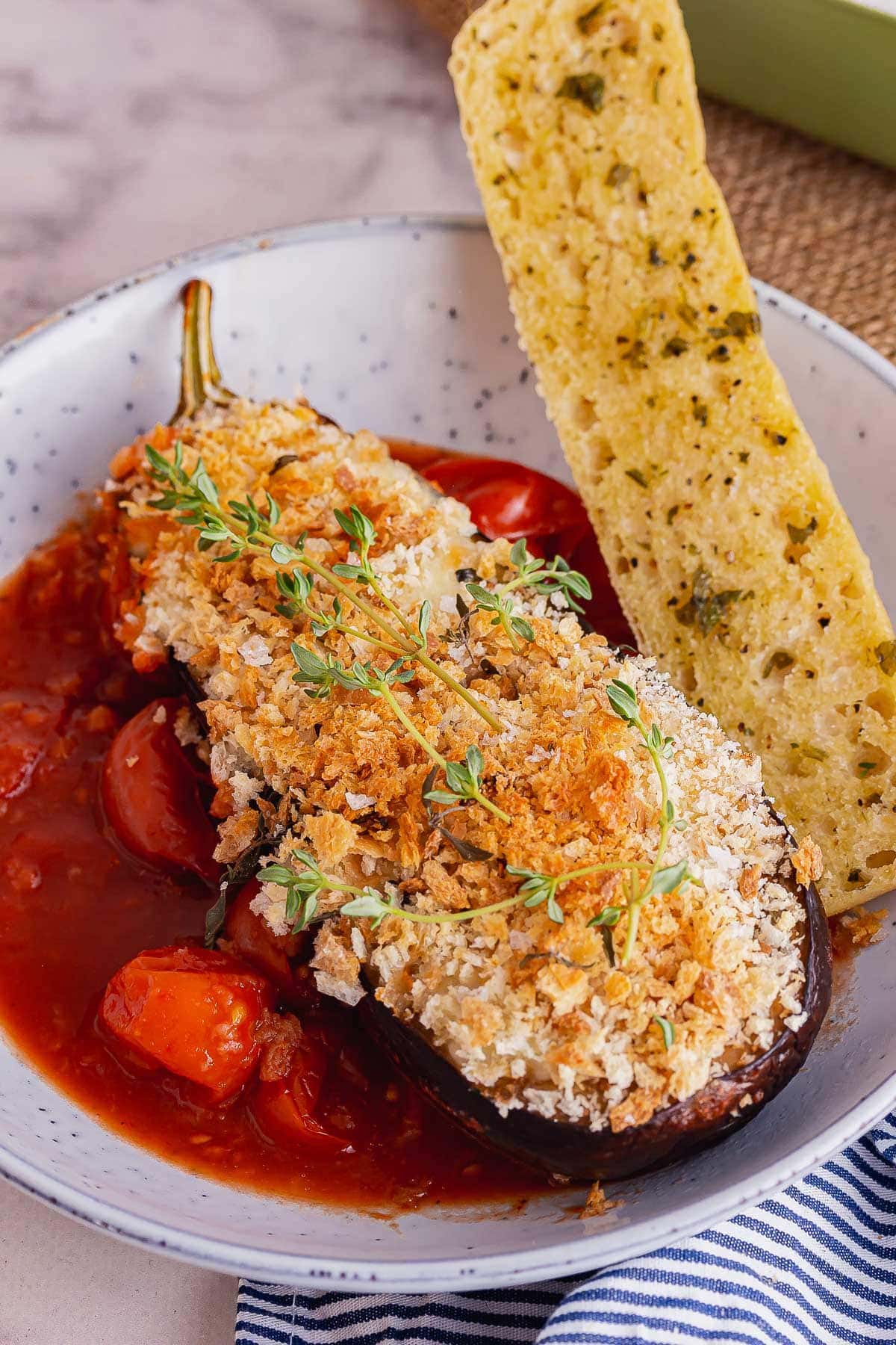 Blue bowl of cheesy roast aubergine with tomato sauce