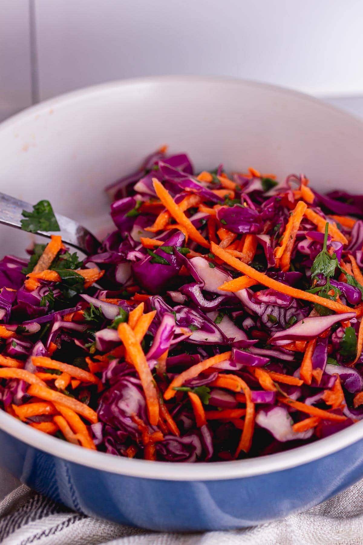 Close up of crunchy slaw with carrots and red cabbage in a blue bowl