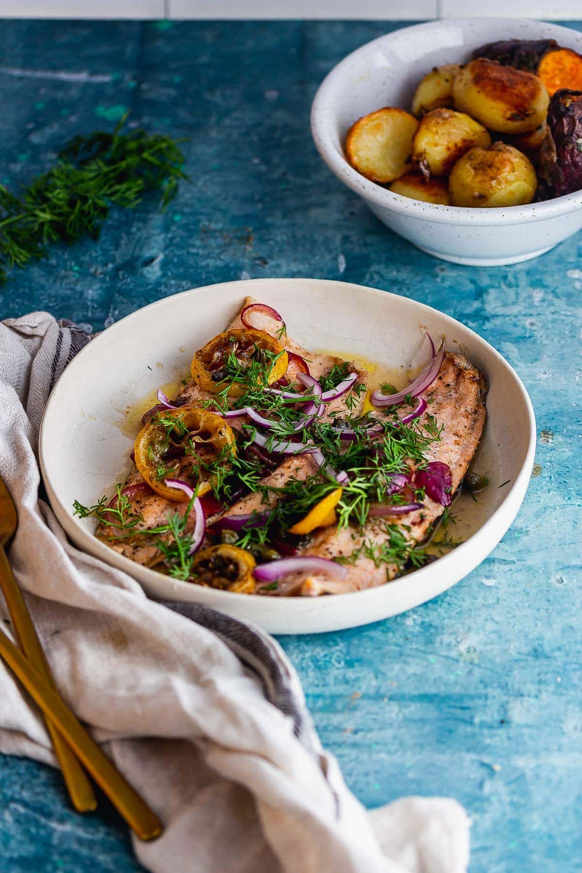 White bowl of baked trout on a blue background