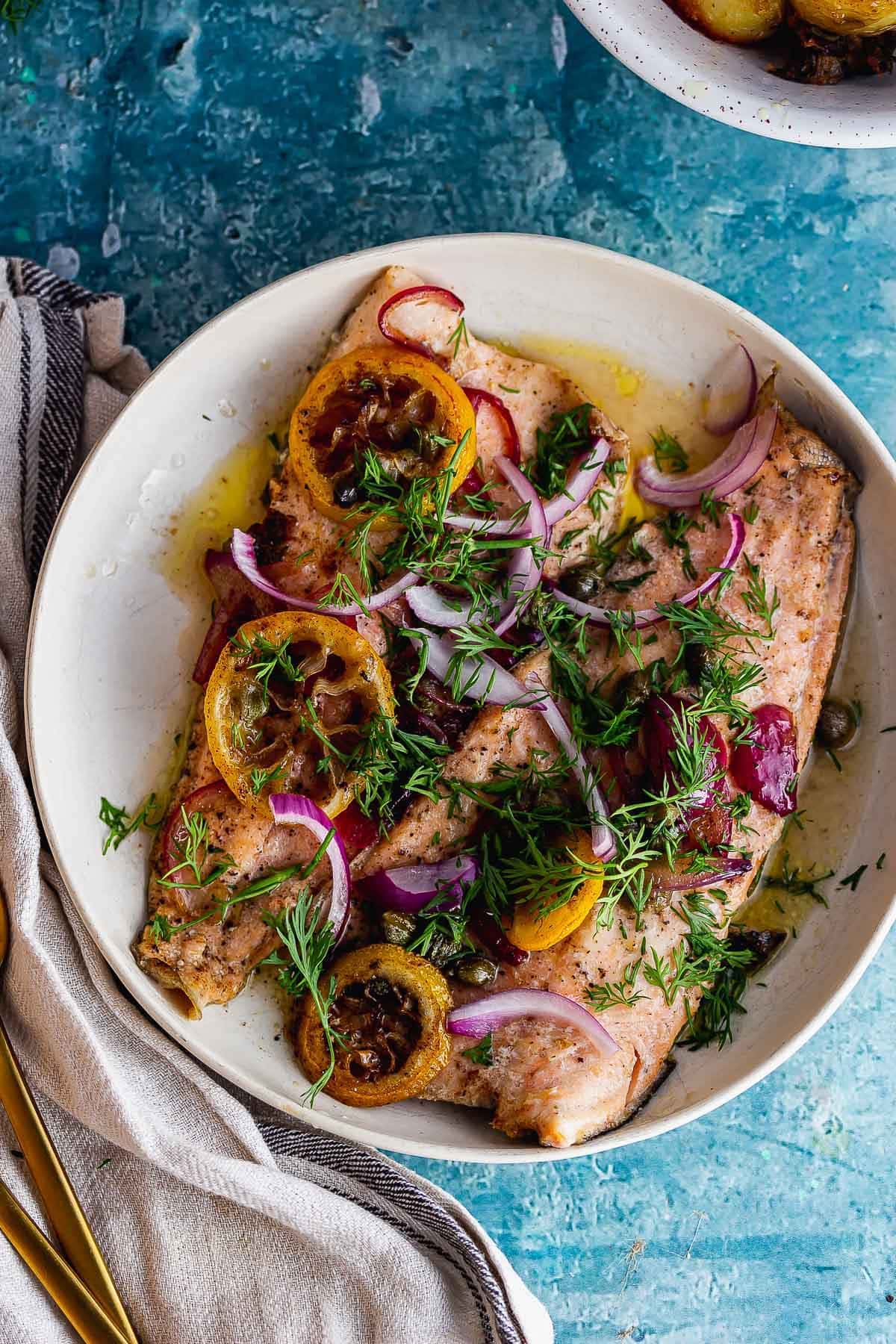 Overhead shot of buttery trout with lemon and red onion