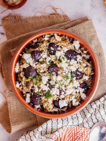 Overhead shot of terracotta bowl of orzo with beetroot and feta