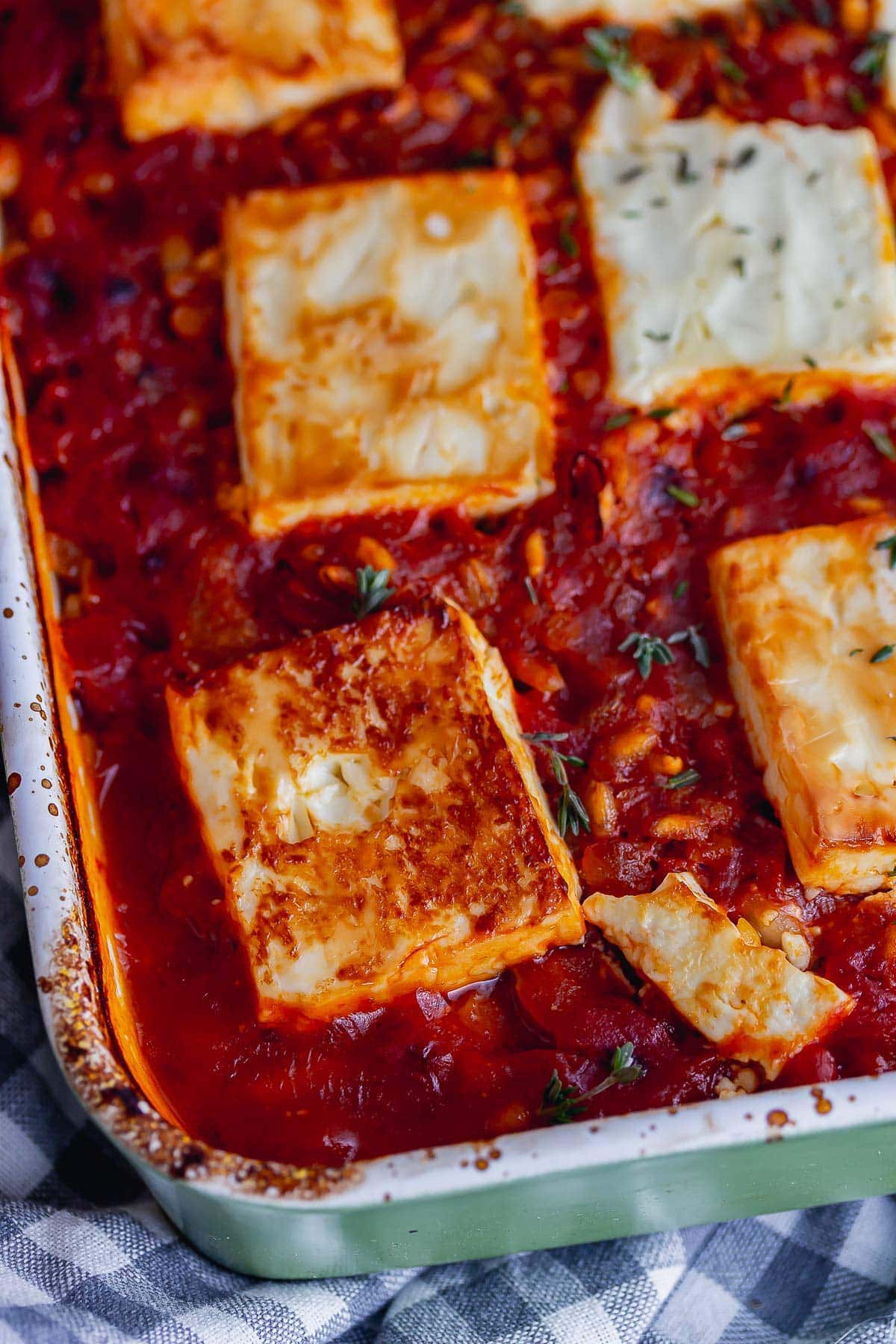 Close up of browned feta on a tomato sauce