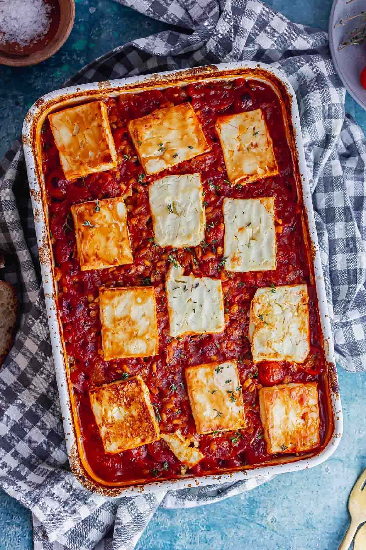 Overhead shot of tomato and feta bake on a checked cloth