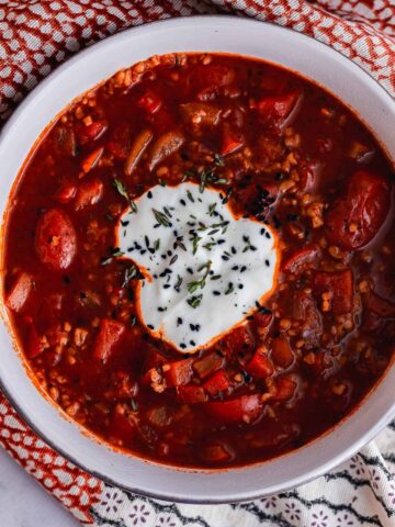 Overhead shot of spiced soup with tomato topped with yoghurt
