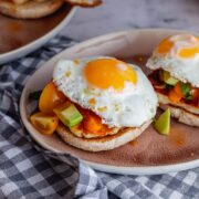 Pink plate of breakfast muffins topped with fried eggs