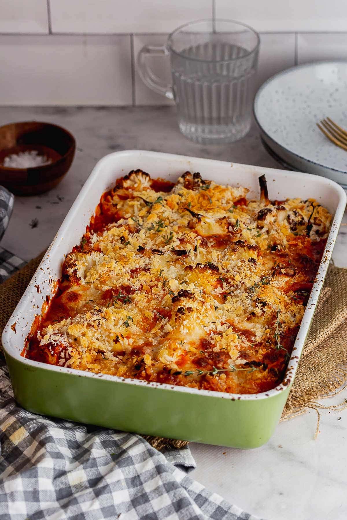 Green baking dish of cauliflower bake on a marble surface