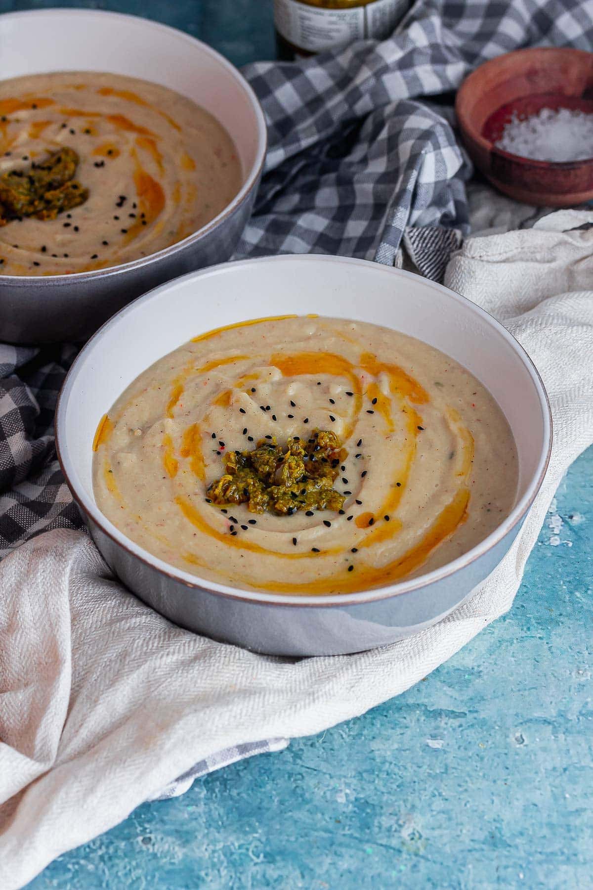 Grey bowl of cauliflower soup on a blue surface