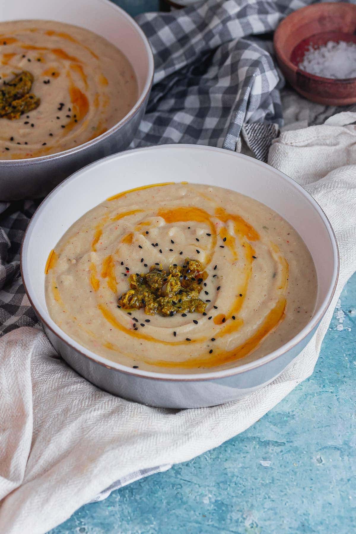 Grey bowl of creamy soup topped with chermoula 