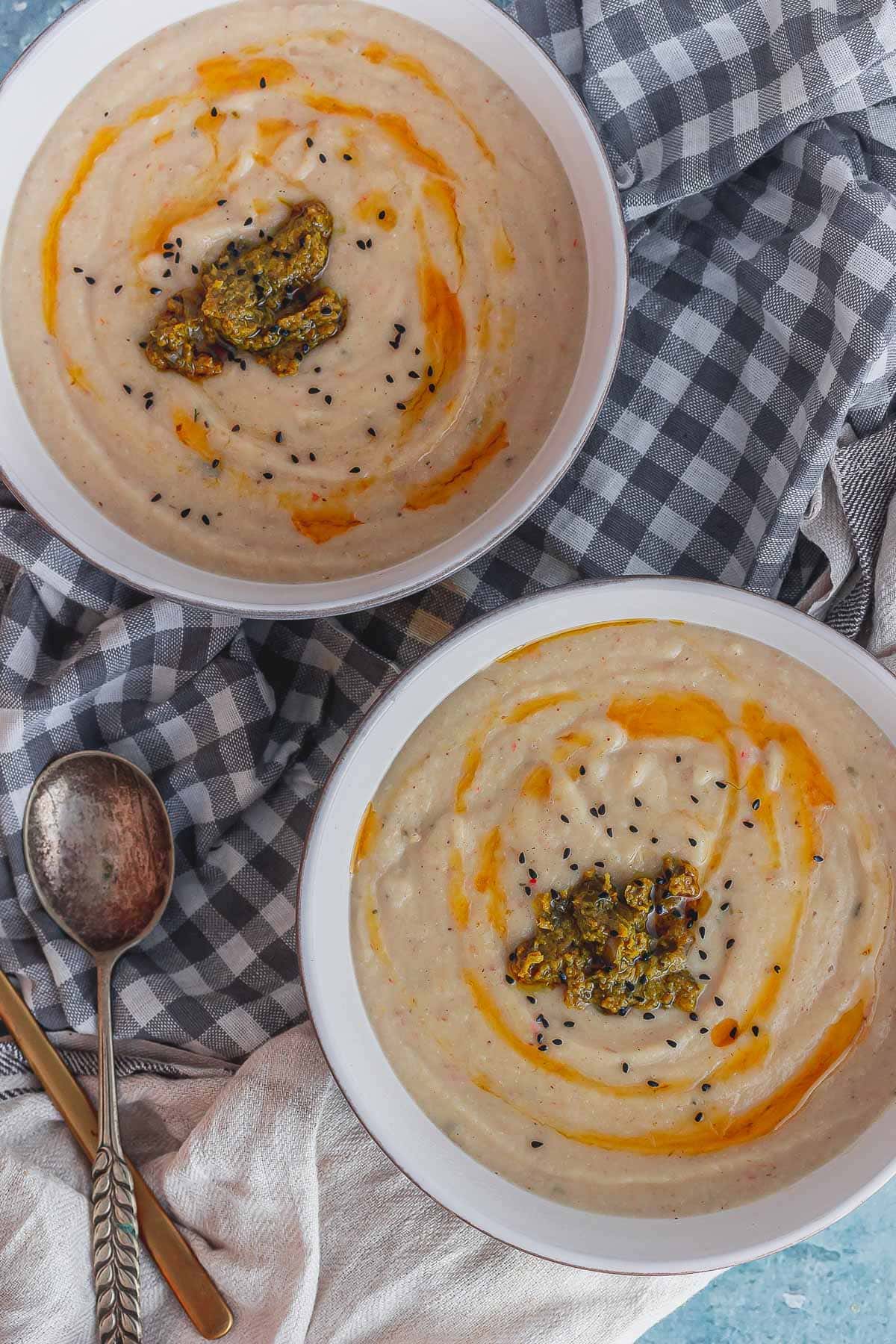 Overhead shot of two bowls of cauliflower and preserved lemon soup on a checked cloth