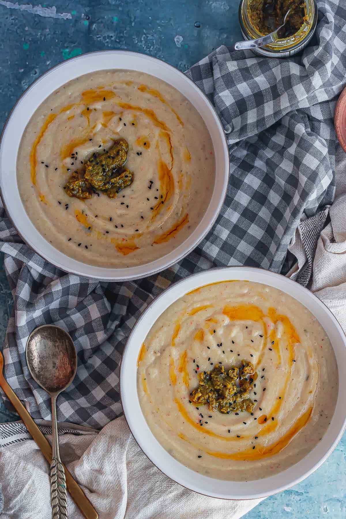 Overhead shot of two bowls of creamy soup on a checked cloth with spoons