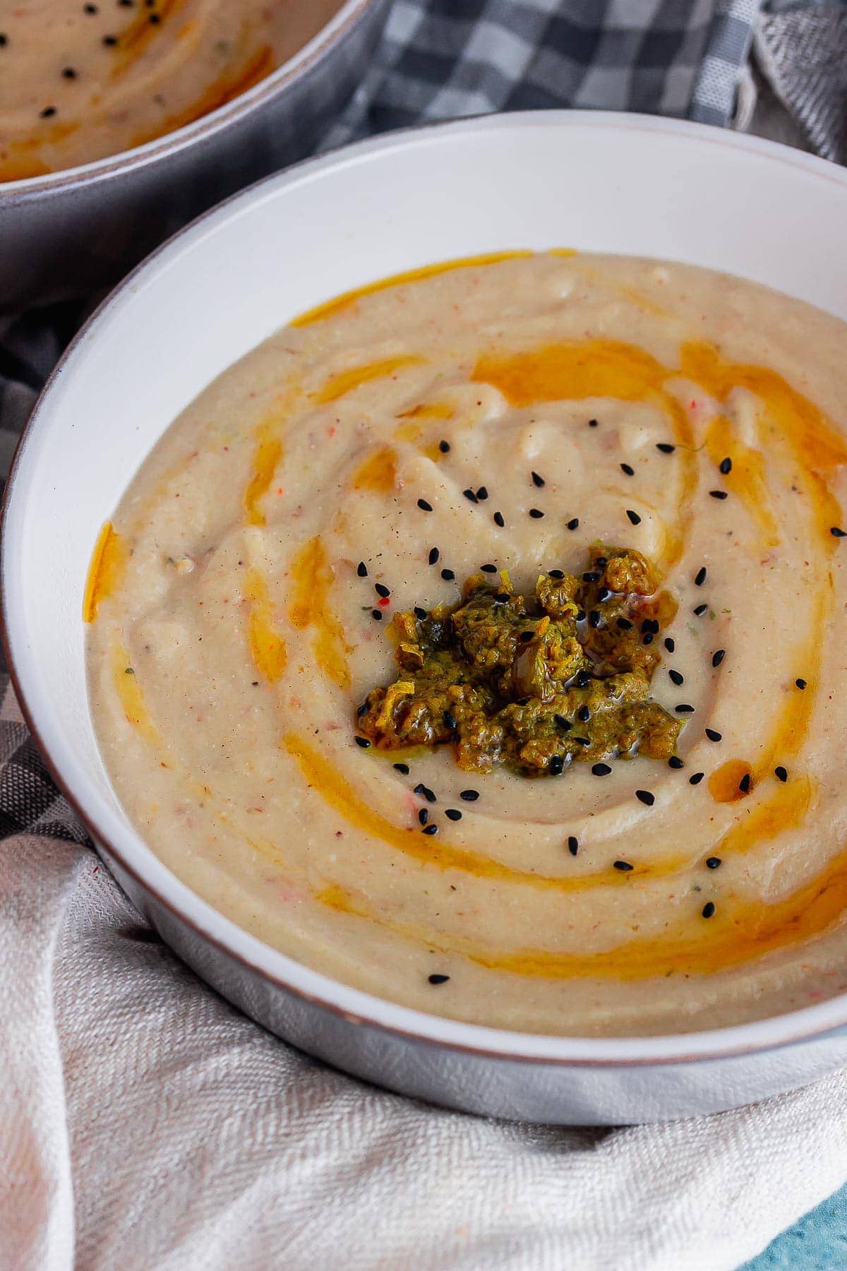 Close up of roast cauliflower soup topped with chilli oil on a beige cloth