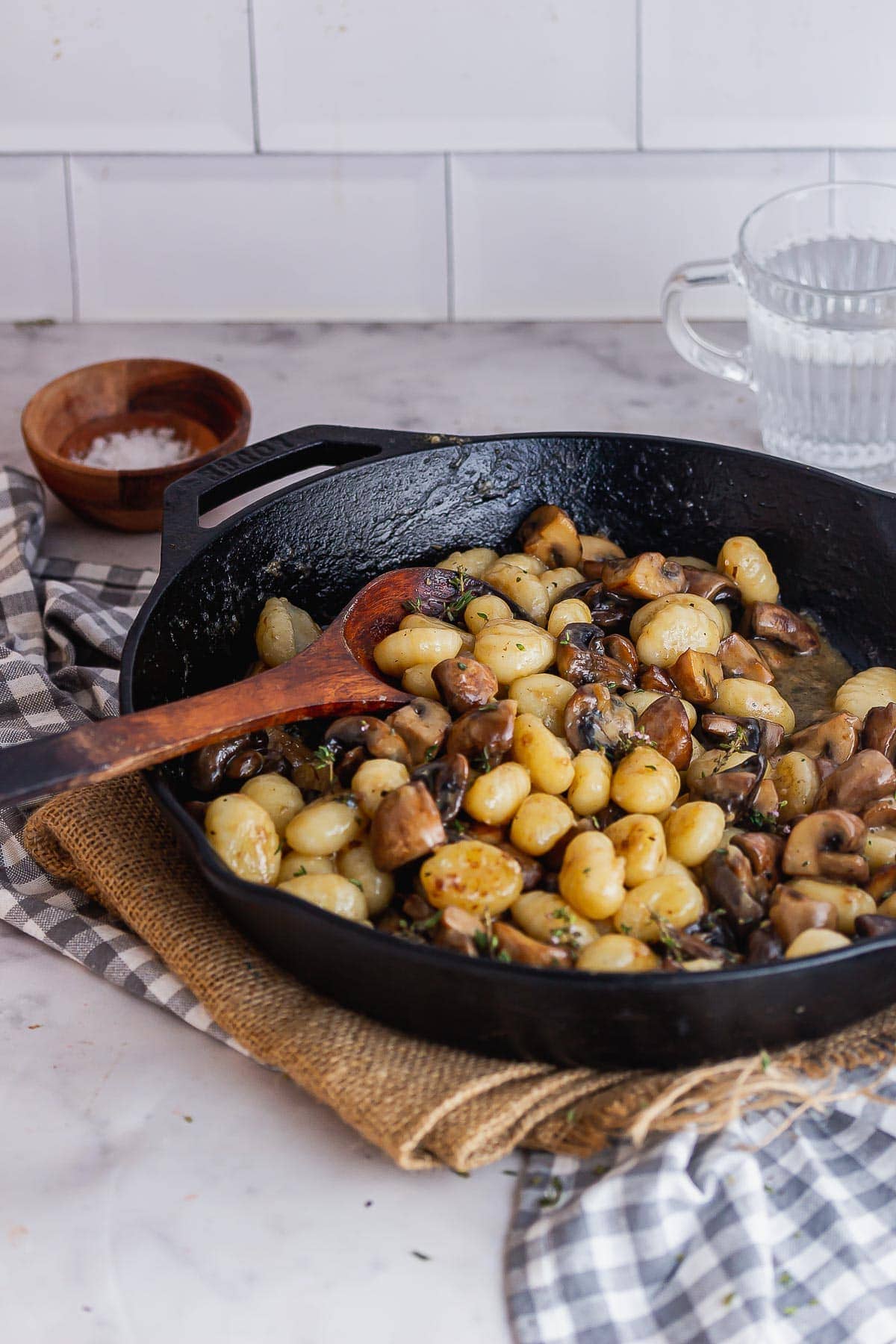 Black skillet of gnocchi with mushrooms on a marble background