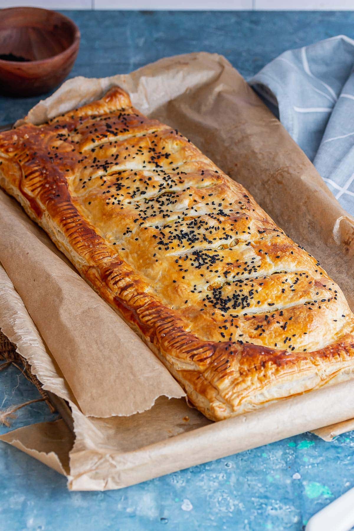 Butternut squash wellington on a baking sheet on a blue background