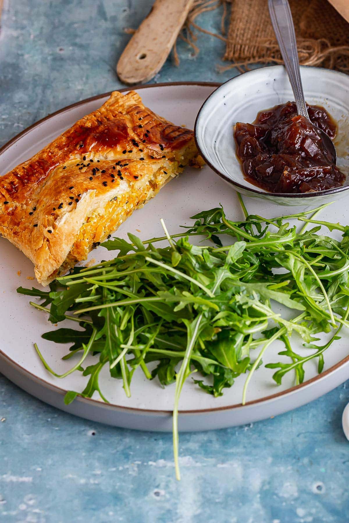 Grey plate with veggie wellington and salad on a blue background