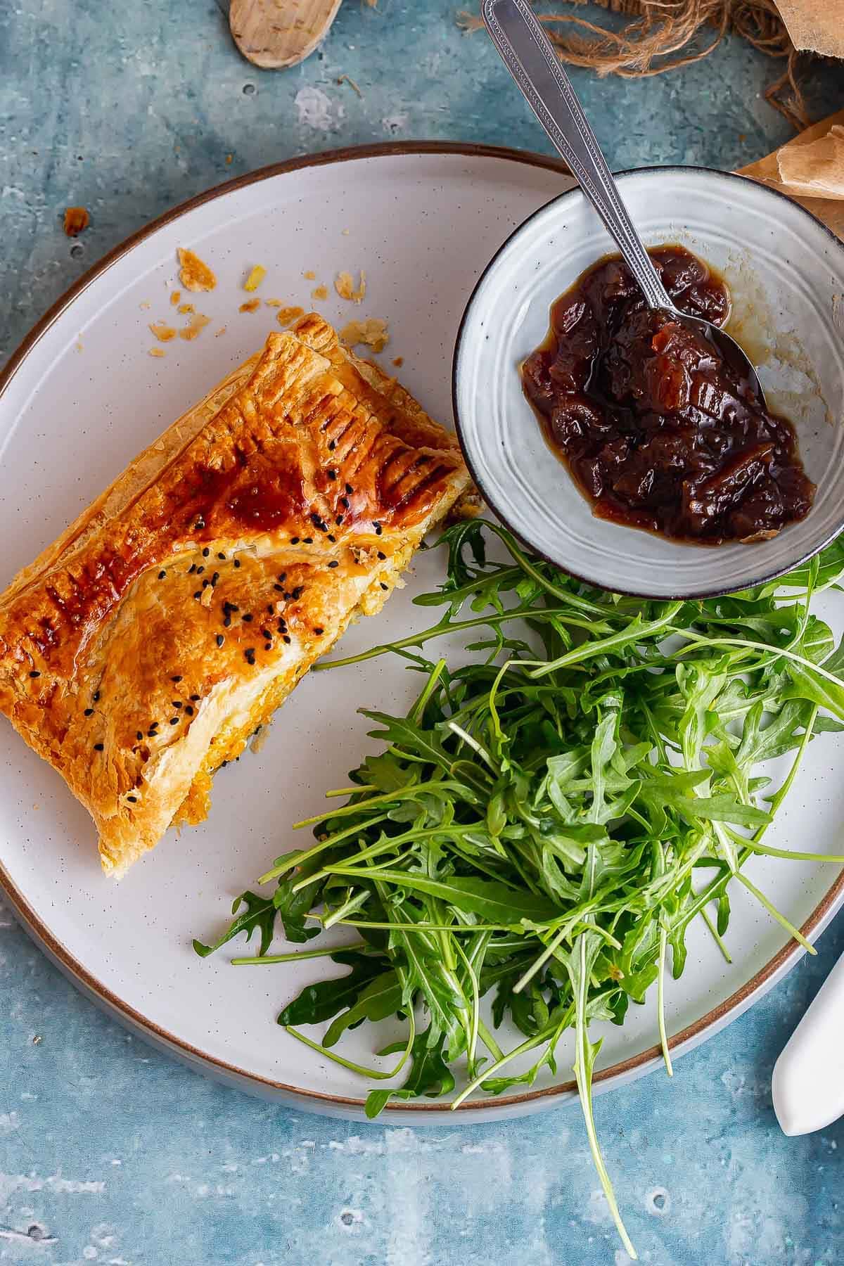 Overhead shot of veggie roll with salad and chutney on a grey plate