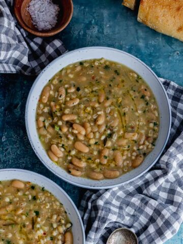 Overhead shot of bean and barley soup on a blue background