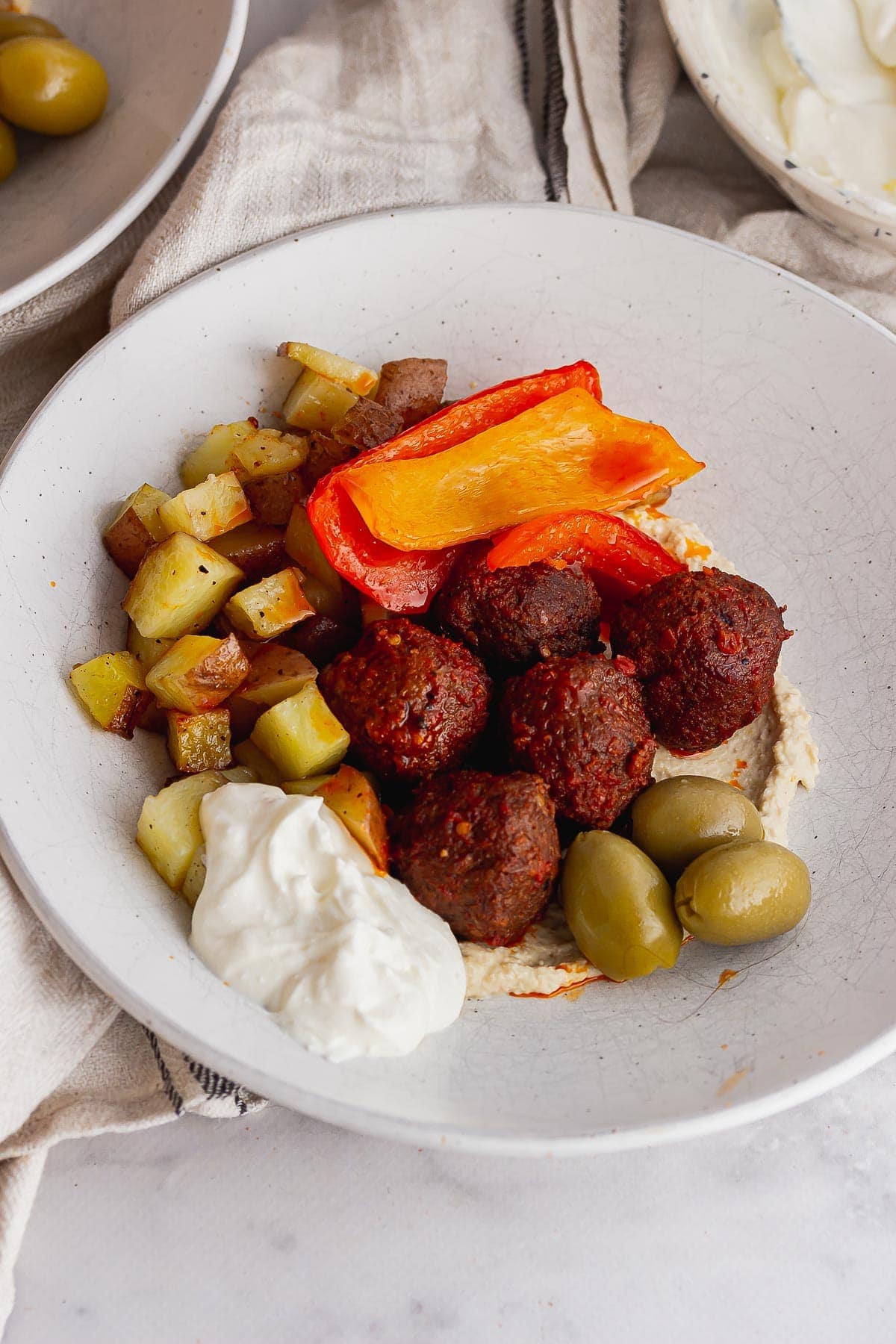 Meatballs and olives in a white bowl