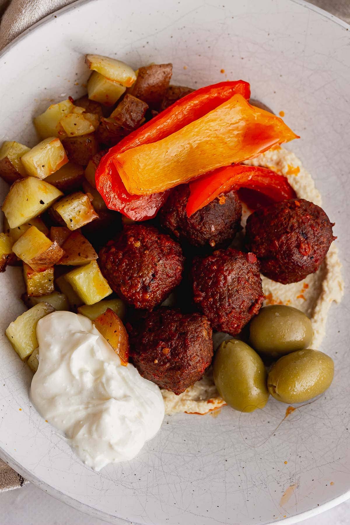 Meatballs and potatoes on a bed of hummus