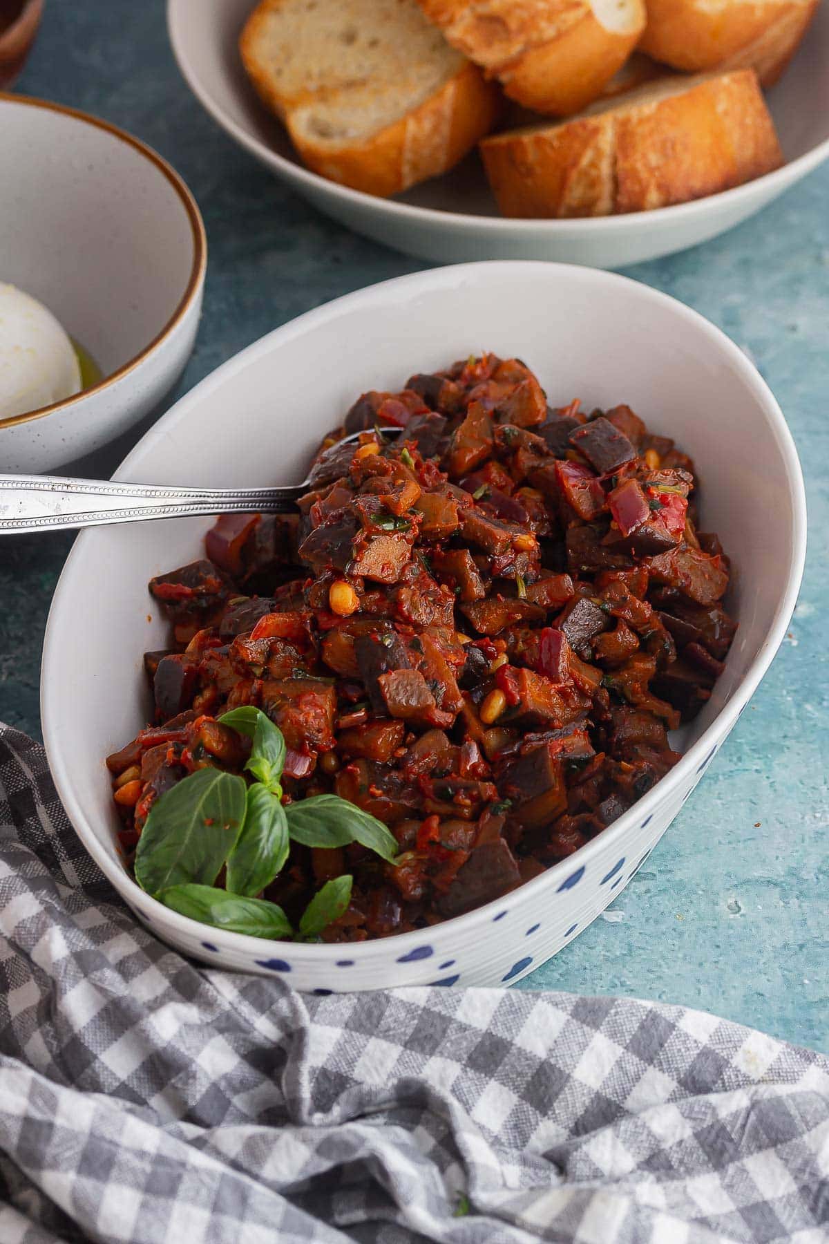 White dish of caponata on a blue background