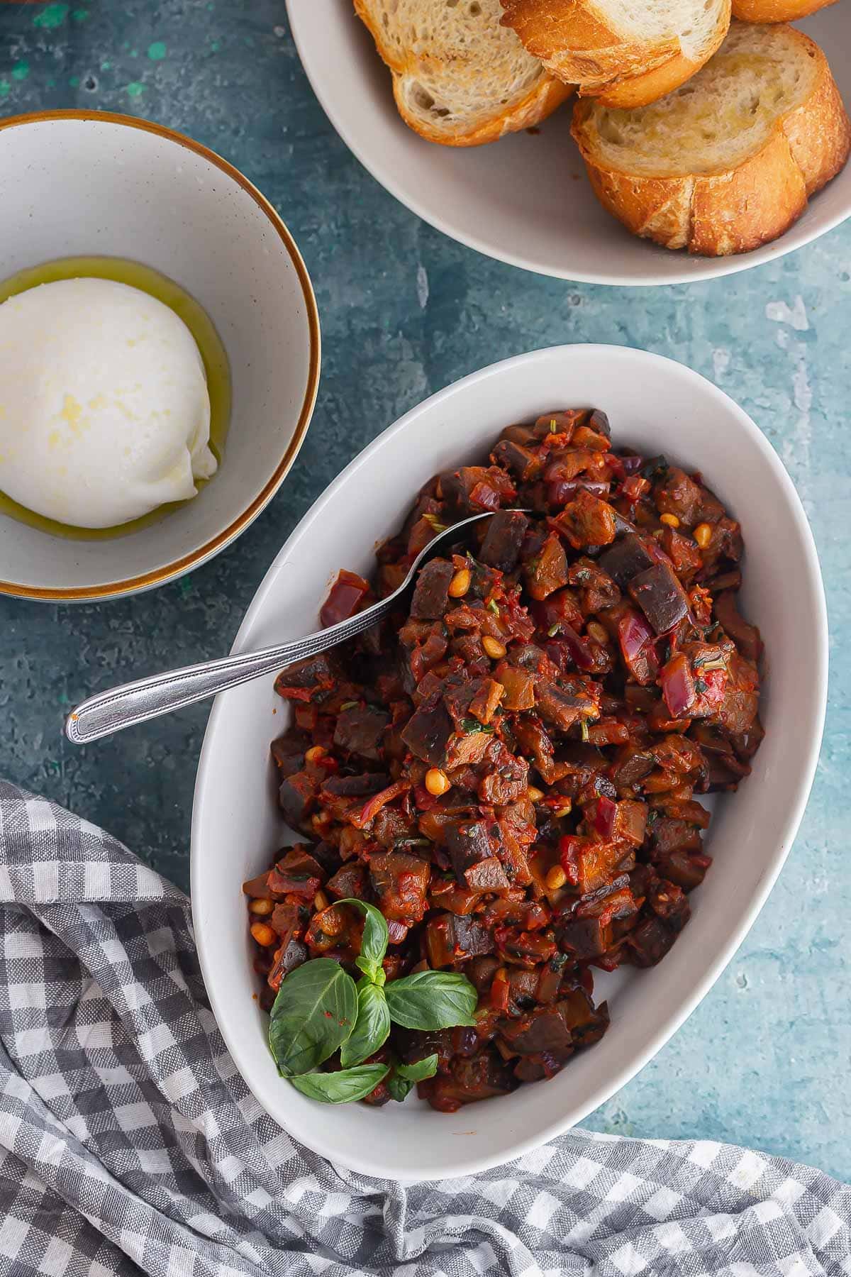 White dish of aubergine stew with toasts and cheese