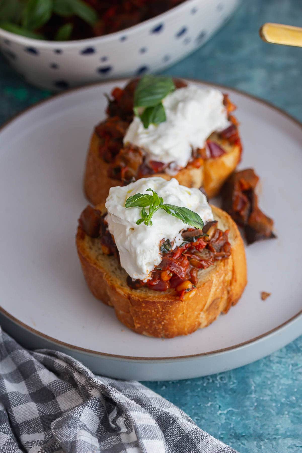 Two toasts topped with caponata and burrata