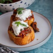 Grey plate of caponata toasts topped with burrata