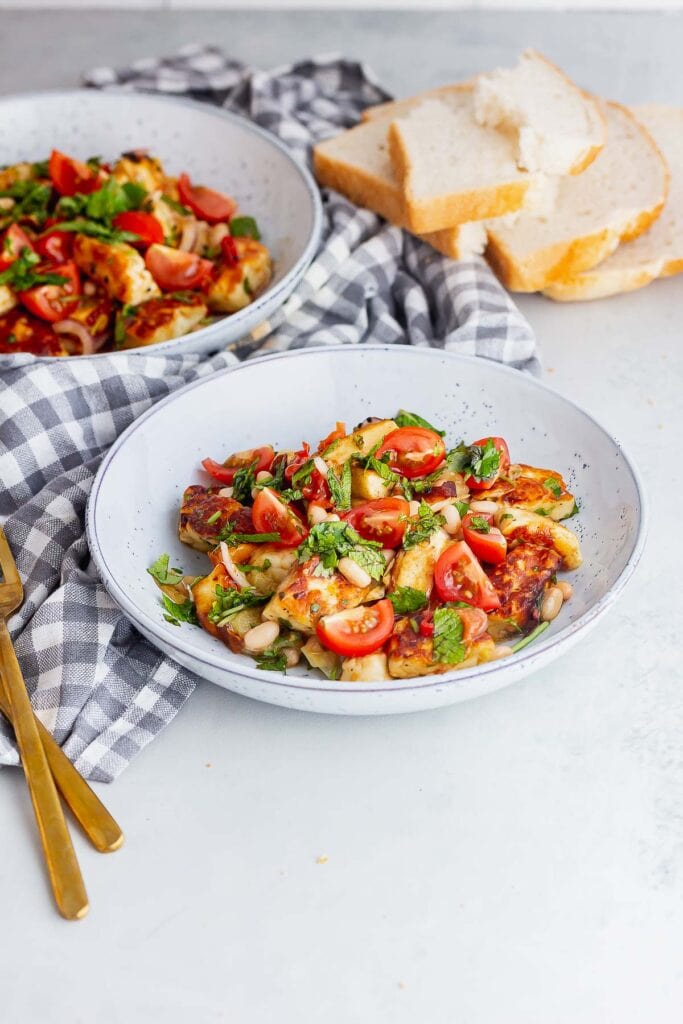 Bowls of halloumi and tomato salad on a grey background