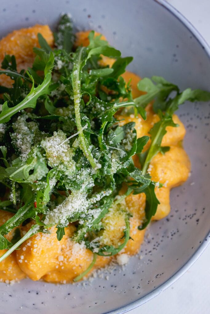 Close up of salad leaves on gnocchi in a blue bowl