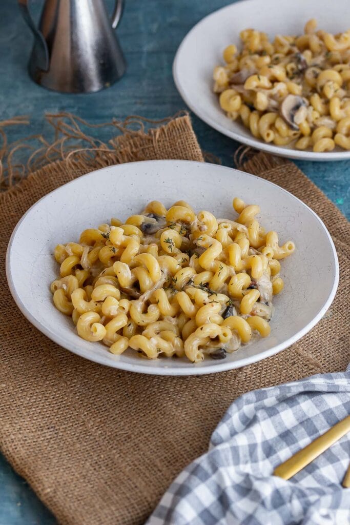 White bowl of caramelised onion pasta on a woven mat