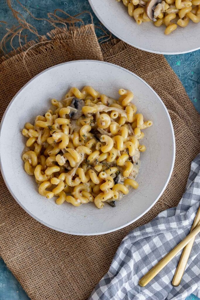 Overhead shot of pasta in a white bowl with a checked cloth