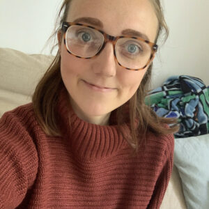 Photo of Amy in a red jumper wearing glasses