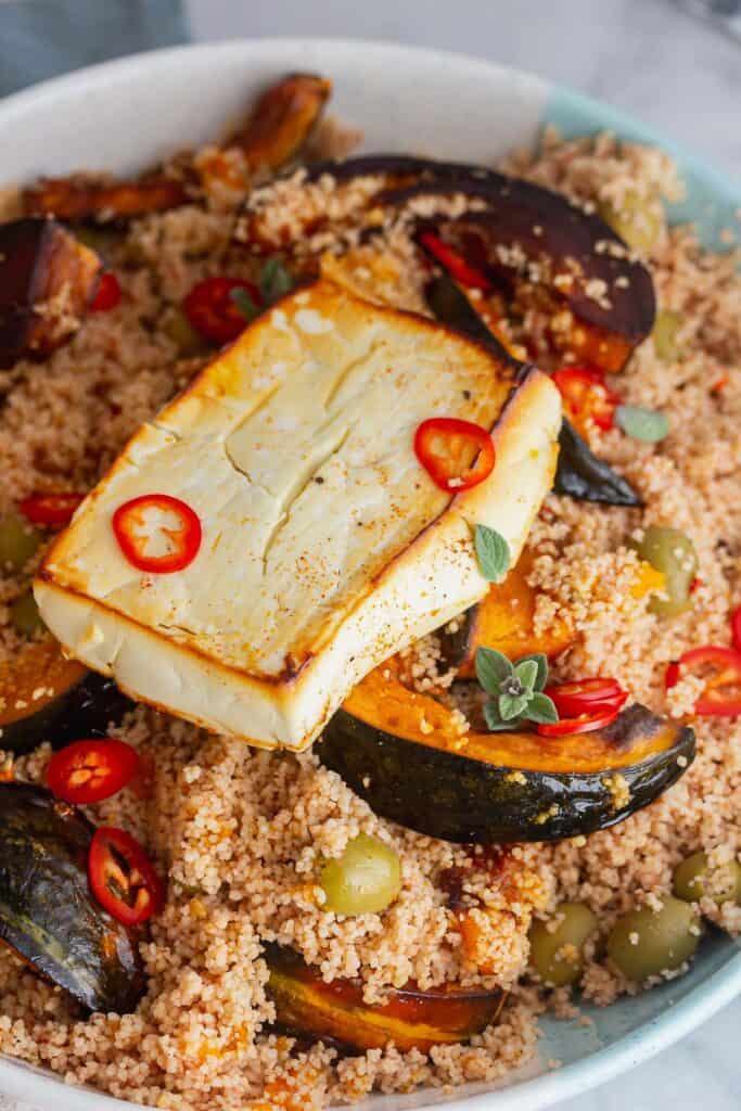 Close up of baked feta on top of a couscous salad