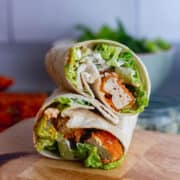 Tofu and salad wrapped in a tortilla on a wooden board