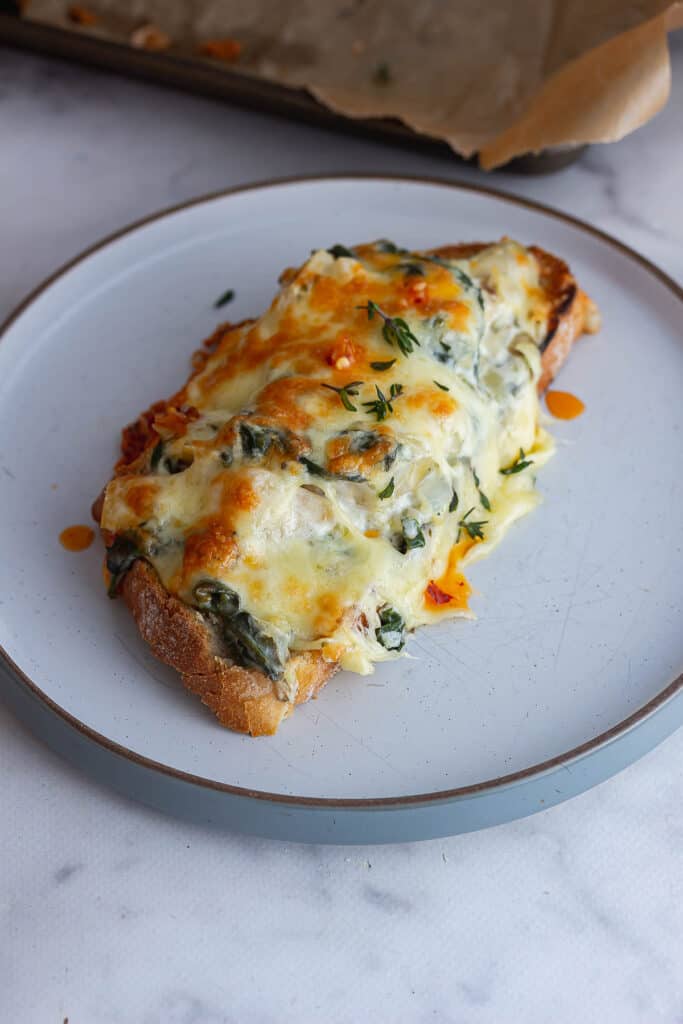 Spinach artichoke toasts on a grey plate on a marble background