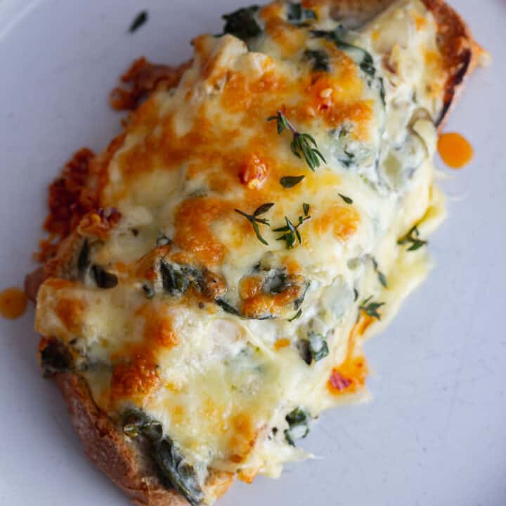 Close up of spinach artichoke toast on a grey plate