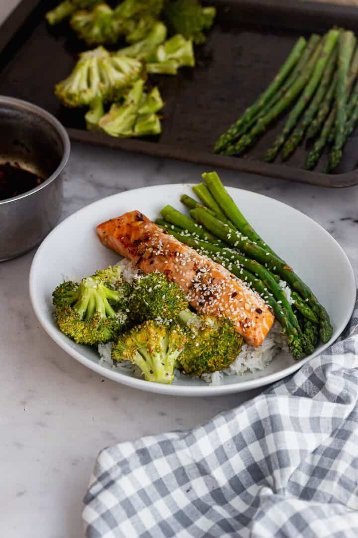 White bowl of salmon and vegetables on a marble surface