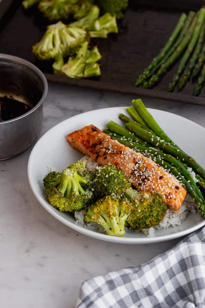 Bowl of salmon and vegetables with baking sheet in the background