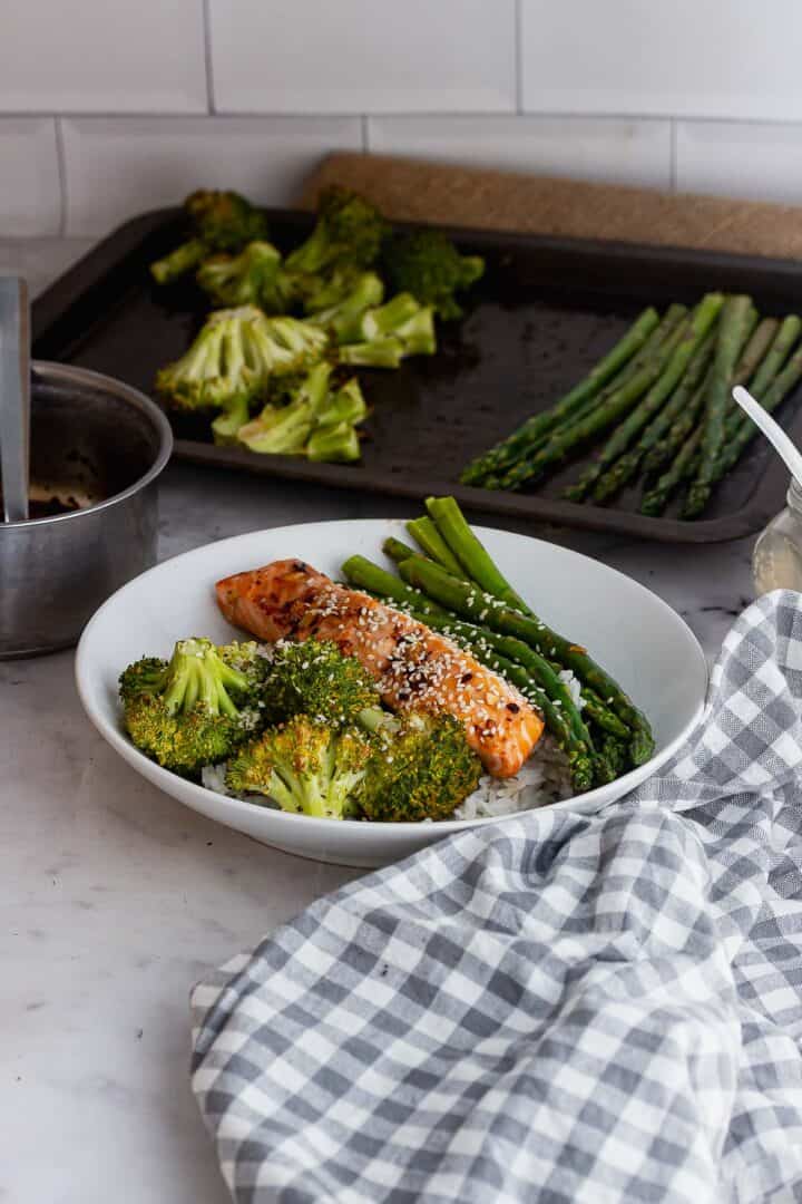 Checked cloth in front of a bowl of salmon and vegetables 